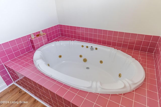 bathroom featuring hardwood / wood-style flooring and tiled tub