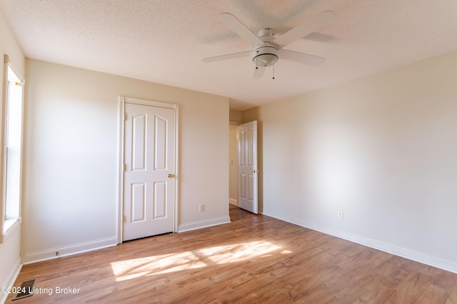 unfurnished bedroom with ceiling fan, a textured ceiling, and light wood-type flooring