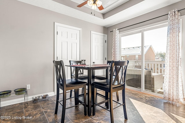 dining room with a textured ceiling, ceiling fan, and a raised ceiling