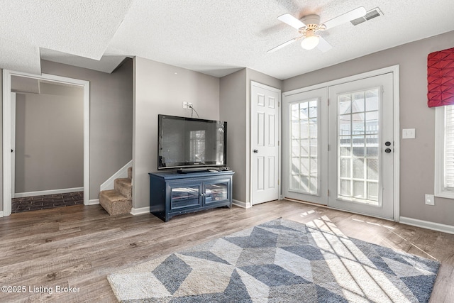 living room featuring ceiling fan, wood-type flooring, and a textured ceiling