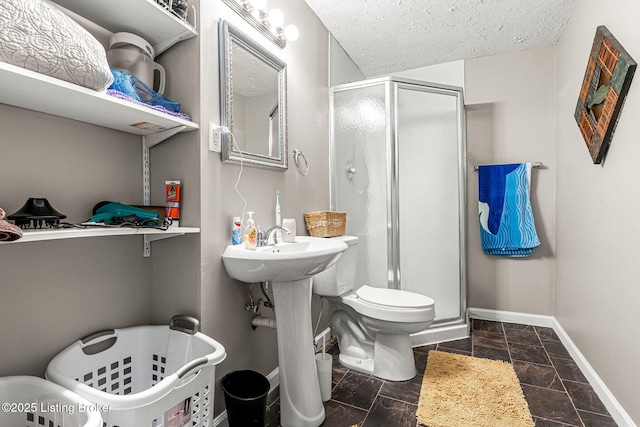 bathroom featuring a textured ceiling, toilet, and a shower with door