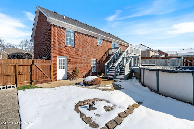 snow covered back of property featuring a wooden deck