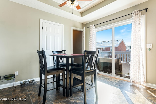 dining space with ceiling fan and a raised ceiling