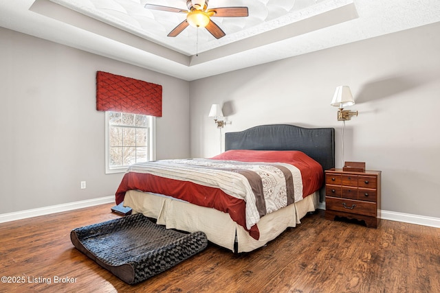 bedroom featuring a raised ceiling, ceiling fan, and dark hardwood / wood-style flooring