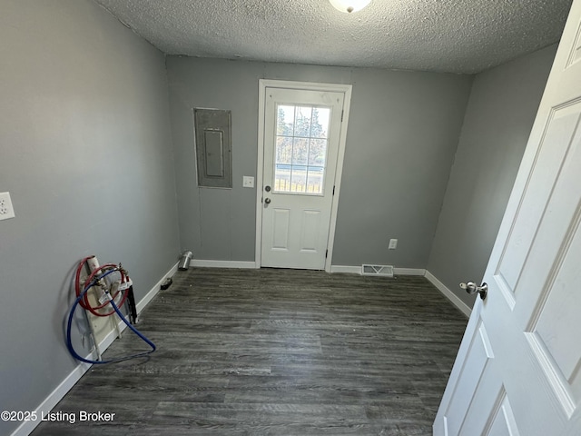 doorway to outside with dark hardwood / wood-style flooring, a textured ceiling, and electric panel