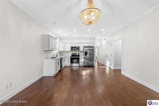 kitchen featuring appliances with stainless steel finishes, dark wood-type flooring, crown molding, a notable chandelier, and white cabinets