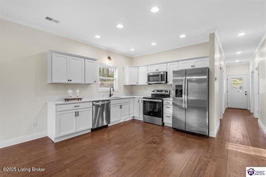 kitchen with backsplash, sink, appliances with stainless steel finishes, dark hardwood / wood-style flooring, and white cabinetry