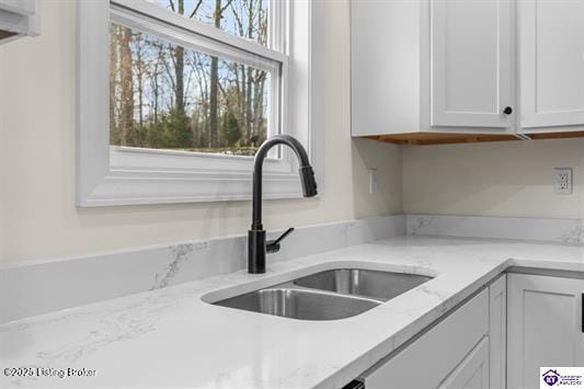 kitchen with white cabinets, light stone countertops, sink, and a wealth of natural light