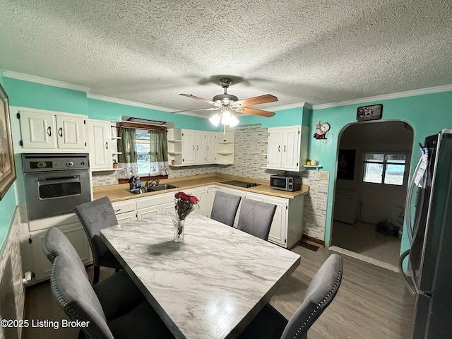 dining space with ceiling fan, sink, hardwood / wood-style flooring, and ornamental molding