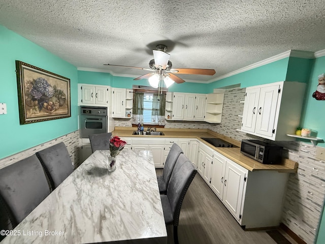 kitchen with sink, white cabinetry, ornamental molding, and stainless steel appliances