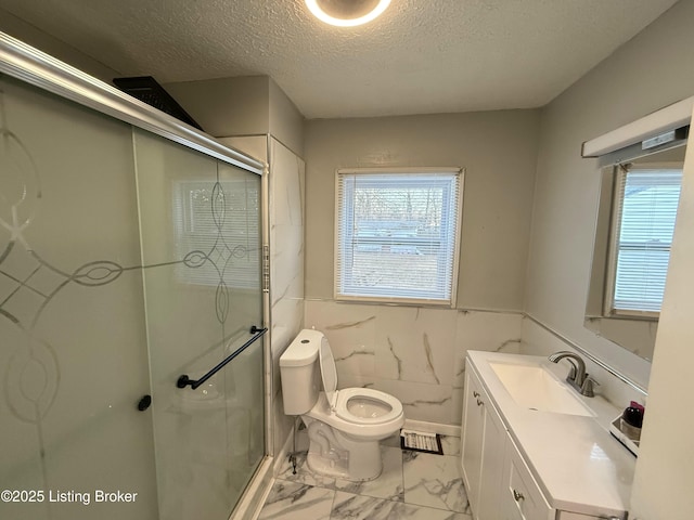 bathroom featuring toilet, a shower with door, tile walls, a textured ceiling, and vanity