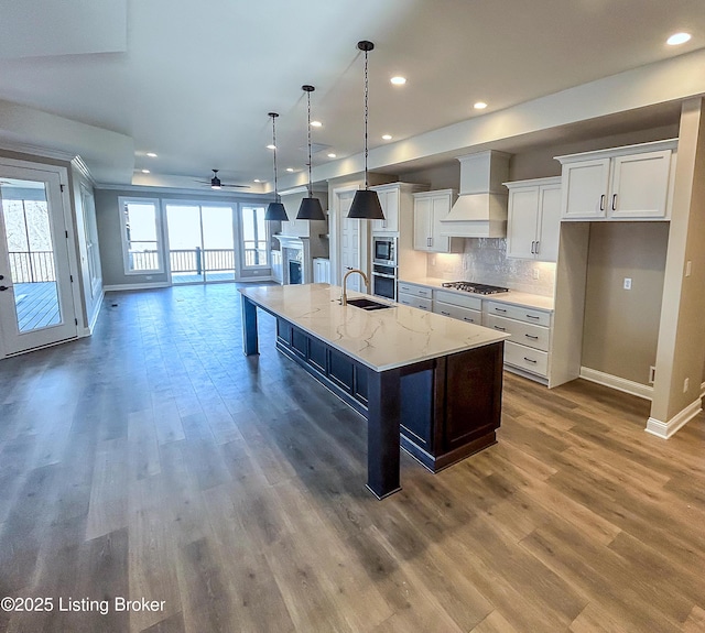 kitchen with custom exhaust hood, white cabinets, a spacious island, ceiling fan, and appliances with stainless steel finishes