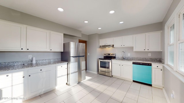 kitchen with white cabinets, stainless steel appliances, light stone counters, and sink