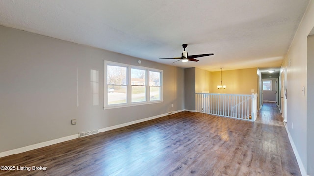 spare room featuring ceiling fan with notable chandelier and dark hardwood / wood-style floors