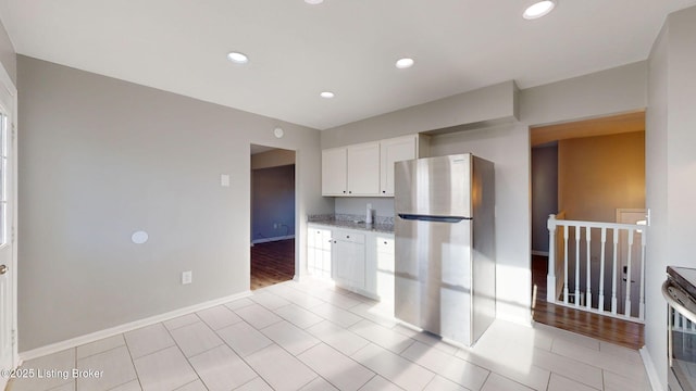 kitchen featuring white cabinets, light tile patterned flooring, light stone countertops, and stainless steel fridge