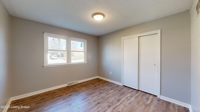 unfurnished bedroom featuring a textured ceiling, light hardwood / wood-style flooring, and a closet