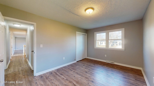 unfurnished bedroom featuring hardwood / wood-style flooring, a textured ceiling, and a closet