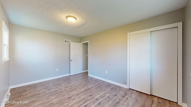 unfurnished bedroom with a closet, light hardwood / wood-style flooring, and a textured ceiling