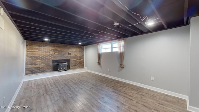 basement with brick wall, a wood stove, and hardwood / wood-style floors