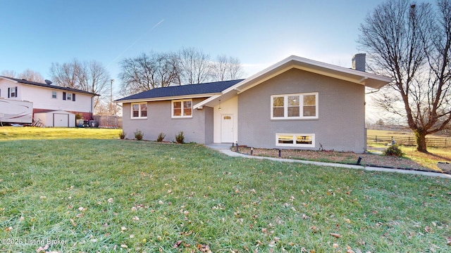 view of front of property featuring a front lawn and a storage shed