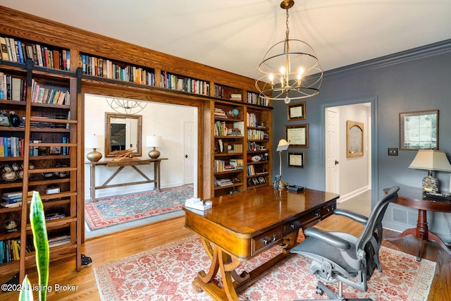 office area with crown molding, a notable chandelier, baseboards, and wood finished floors