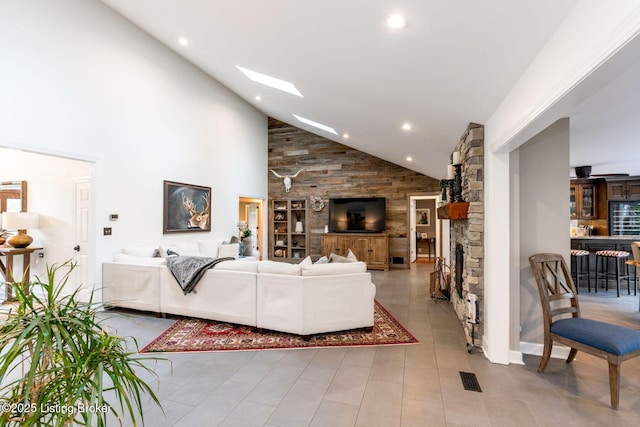 living area featuring high vaulted ceiling, recessed lighting, a skylight, a fireplace, and visible vents