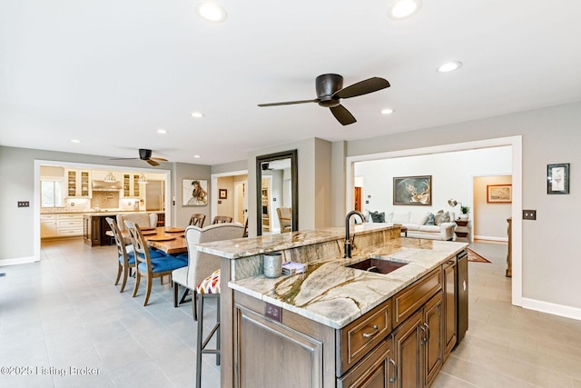 kitchen with an island with sink, a breakfast bar area, a sink, and recessed lighting