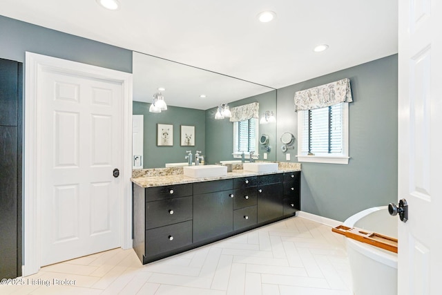 full bath with double vanity, a soaking tub, a sink, and recessed lighting