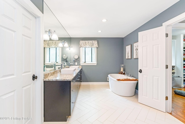 full bathroom featuring recessed lighting, a soaking tub, vanity, and baseboards