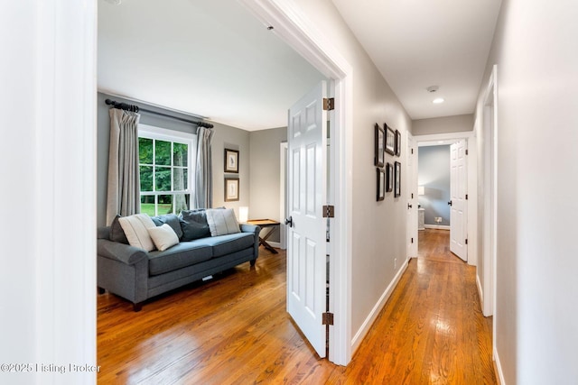 corridor with light wood-style flooring and baseboards