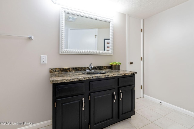 bathroom featuring a textured ceiling, tile patterned floors, vanity, and baseboards