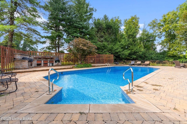 view of pool with a patio area, an outdoor kitchen, and fence