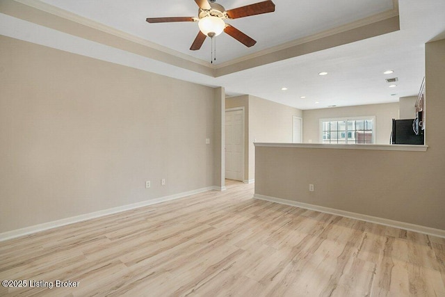 spare room featuring light hardwood / wood-style floors, a raised ceiling, ceiling fan, and crown molding