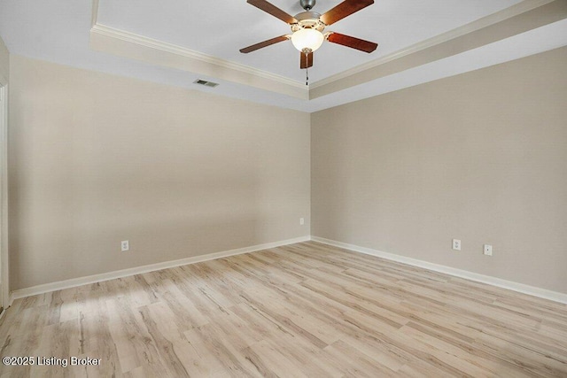 empty room featuring a tray ceiling, ceiling fan, light hardwood / wood-style flooring, and ornamental molding