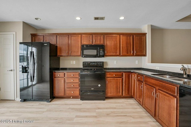 kitchen with sink, black appliances, and light hardwood / wood-style floors