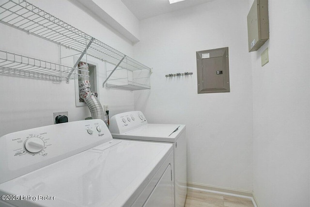 laundry room featuring electric panel, washing machine and dryer, and light wood-type flooring