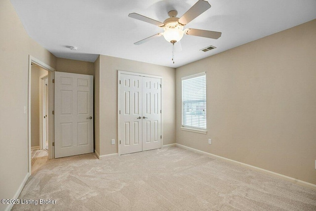 unfurnished bedroom featuring light colored carpet, a closet, and ceiling fan