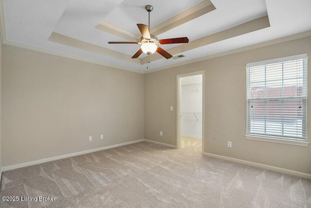 carpeted empty room featuring a tray ceiling, ceiling fan, and crown molding