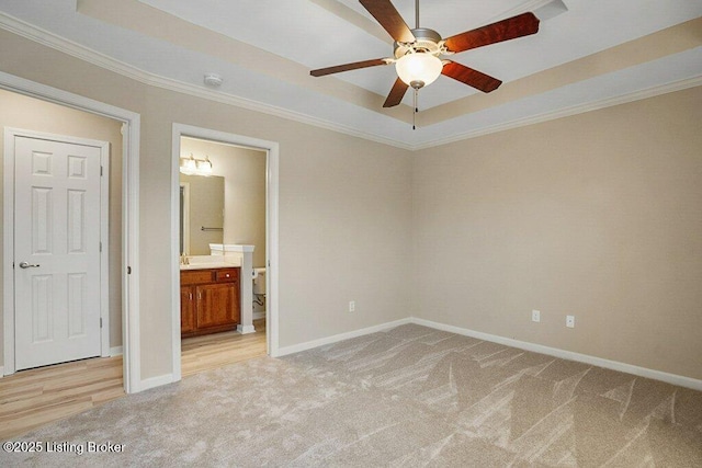 unfurnished bedroom with a tray ceiling, ensuite bathroom, ceiling fan, and light colored carpet