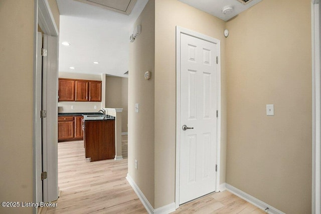 corridor with light hardwood / wood-style flooring and sink