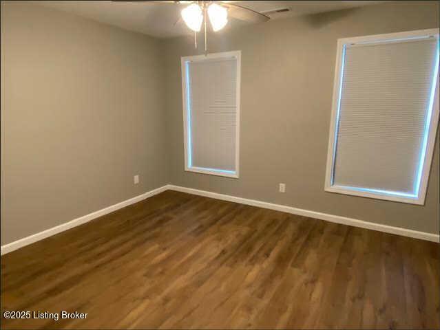 empty room with ceiling fan and dark wood-type flooring