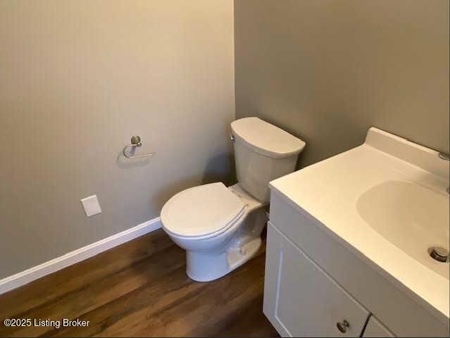 bathroom with wood-type flooring, toilet, and vanity