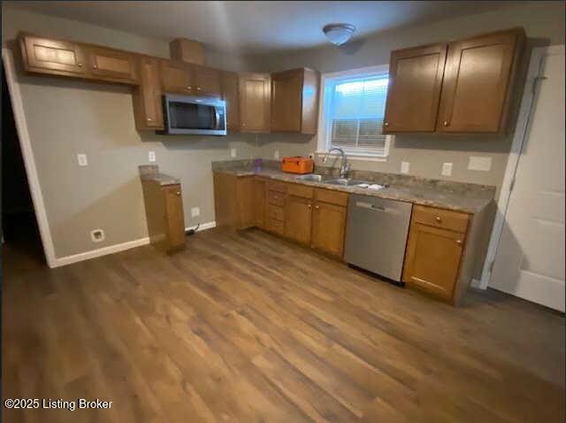 kitchen with appliances with stainless steel finishes, hardwood / wood-style floors, and sink