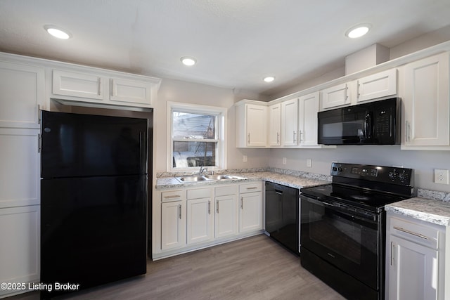 kitchen featuring light stone counters, sink, black appliances, light hardwood / wood-style flooring, and white cabinetry