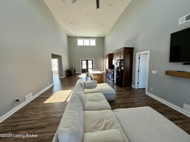 living room featuring a high ceiling, dark wood-type flooring, and sink