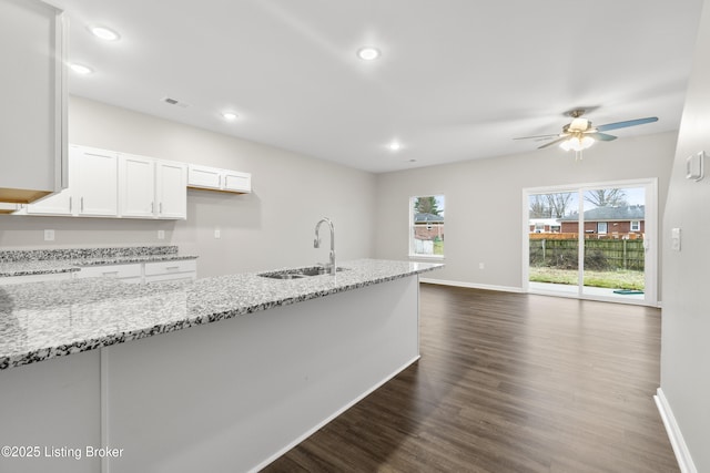 kitchen with white cabinetry, light stone countertops, sink, ceiling fan, and dark hardwood / wood-style floors