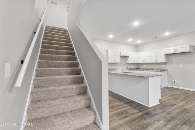 stairs featuring hardwood / wood-style floors and sink