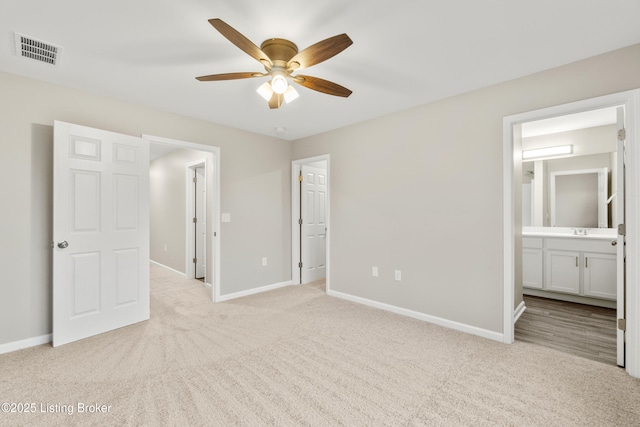 unfurnished bedroom featuring light carpet, connected bathroom, ceiling fan, and sink