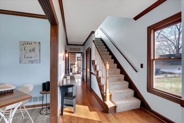 stairs featuring hardwood / wood-style floors and ornamental molding