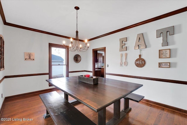 dining area with dark hardwood / wood-style flooring, an inviting chandelier, and ornamental molding